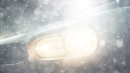 Wall Mural - snowfall, car, background in a snowstorm with a copy of the space, the headlights of an oncoming car through a thick snowfall, winter view on the highway, headlight light