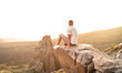 Wanderer sitzt auf einem großen Felsen und genießt den Sonnenuntergang