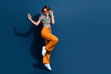 Wall Mural - Full body photo of pretty young girl dancing have fun energetic wear trendy flared pants jeans isolated on dark blue color background