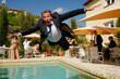 A suited groom accidentally falls into a swimming pool at a wedding party. Confusion at a wedding party in a villa.