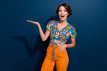 Wall Mural - Photo of young girl fashion designer holding arm demonstrate her retro style outfit surprised reaction isolated on blue color background