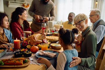 Happy grandmother talks to her granddaughter during Thanksgiving family meal.