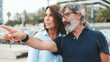 Elderly couple in love standing on the embankment and pointing at something