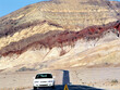 Car at desert road with colored mountains