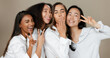 © N Felix/peopleimages.com - Diversity, peace sign and group of women in studio for empowerment, wellness and community. Emoji, friends and people hug, blow kiss and smile for beauty, inclusion and support on brown background