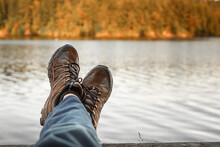 Man With Hiking Shoes Relaxing By An Autumn Mountain Lake. Adventure And People Finding Peace Alone In Nature 