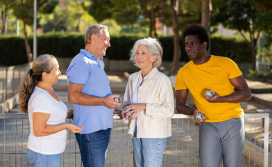 Two adult couples share their impressions after playing petanque outdoors