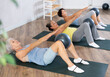 © JackF - Smiling mature woman doing pilatess lying on black mat with soft ball between legs during fitness classes
