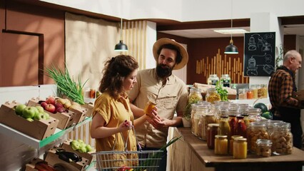 Canvas Print - Portrait of happy vegan couple buying pantry staples from zero waste supermarket. Smiling clients shopping for bulk food products in reusable jars from local neighborhood store, zoom in shot