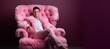 © Margo_Alexa - A young man in a pink suit and shoes sits comfortably on a fluffy soft fur pink chair.