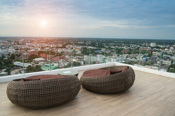 Woven wicker seamless pattern table and chairs is basketwork by weaving plastic strands to oval or sphere shape . Brown wicker sofa on the rooftop for see view of the city with sunlight background.