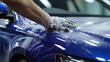 Close-up shot of a worker's hands gripping a car wash sponge as they meticulously clean a vehicle