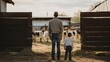 A father and son on a farm, observing the animals, seen from behind.