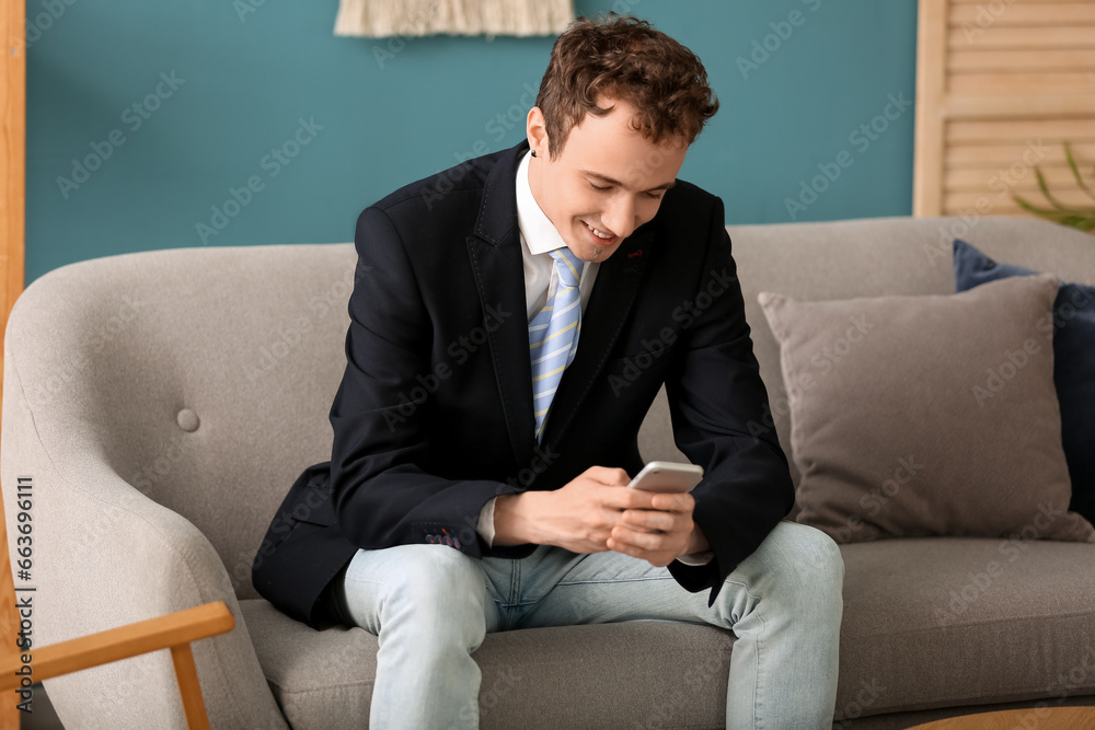 Young businessman with smartphone sitting on sofa