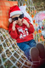 Wall Mural - baby in santa claus hat and sunglasses lying on a hammock