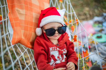 Wall Mural - baby in santa claus hat and sunglasses lying on a hammock