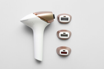 Modern photoepilator with attachments on grey background