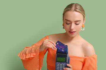 Poster - Pretty young woman with credit card and payment terminal on green background