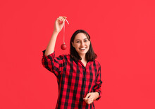 Beautiful Young Woman In Pajamas With Christmas Ball On Red Background