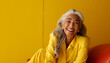 © RJ.RJ. Wave - Portrait of a happy smiling beautiful aging mature woman with smooth healthy face skin and long gray hair on  bright solid yellow background with empty copy space