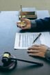 © ArLawKa - Male lawyer working with contract documents and wooden hammer on table in courtroom, justice and law, court judge, justice lawyer concept, legal advice and service vertical picture
