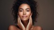 © koplesya - a beautiful curly young mulatto woman with clean fresh skin touches her own face. Facial care. Cosmetology, beauty and spa