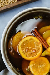 Pot of hot cider wassail with sliced fruits and whole spices for winter dinners