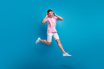 Canvas Print - Full length portrait of carefree overjoyed person jumping hands touch headphones isolated on blue color background