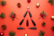 Christmas tree made of lipsticks with festive decorations on red background. Christmas sale of beauty cosmetic products concept.
