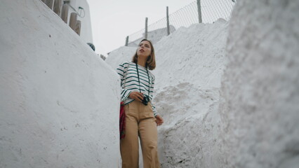 Girl walk white street in old mediterranean city. Travel blogger making photos