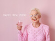 happy caucasian senior woman in cashmere pink sweater drinking rose on pink background. Celebrating, love, retirement, mature concept 