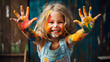 Joyful girl laughing and showing hands with colorful paint