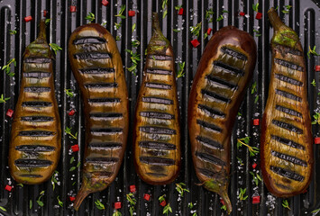 Wall Mural - halves grilled eggplant, with chilli pepper and spices, top view. Ideas for barbecues and grill parties.