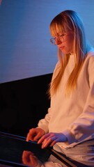 Vertical video of Adolescent girl using touch screen display, skillfully searching interactive content on the modern museum exhibition, medium side view. Digital technology concept.