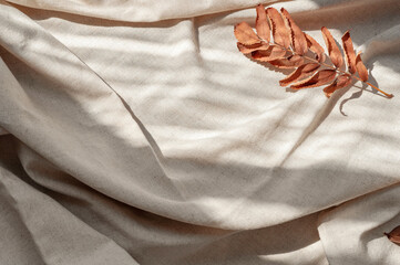 Fall leaves and natural sunlight shadows on crumpled linen cloth background