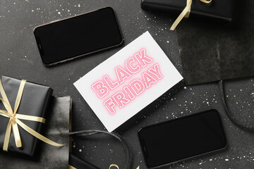 Poster - Black Friday sale greeting card with mobile phones, gift boxes and shopping bags on dark grunge background