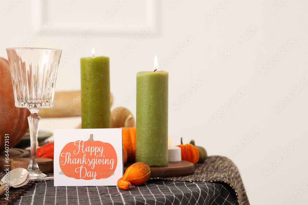 Festive table setting for Thanksgiving Day with pumpkins, greeting card and burning candles
