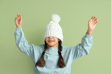 Poster - Cute little girl in warm hat on green background