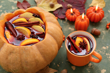 Wall Mural - Mulled wine in pumpkin and mug of tasty drink on green background