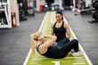 © Dusan Petkovic - A happy female coach is training sportswoman in a gym who is doing situps.