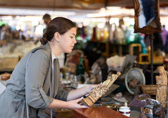 Happy young woman buying retro and antique handicrafts on flea market