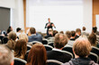 © kasto - Speaker giving a talk in conference hall at business event. Rear view of unrecognizable people in audience at the conference hall. Business and entrepreneurship concept