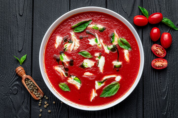 Wall Mural - Summer cold tomato vegetable soup Gazpacho with mozzarella cheese on the black table. Vegetarian cuisine.