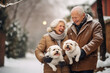 © Anna - The elderly silver-haired man and woman are outdoors in a winter landscape, holding two adorable white puppies in their arms.