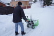 © Liubov - A man cleans snow in the winter in the courtyard of the house,  man cleaning snow with a snow blower