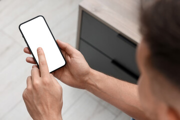 Wall Mural - Man using mobile phone indoors, closeup view