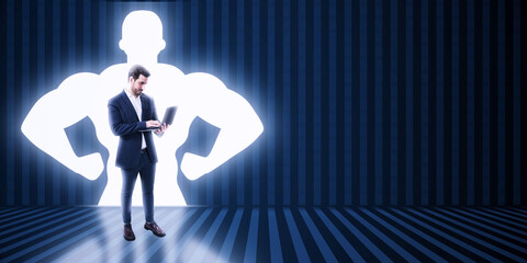 Canvas Print - Businessman with laptop and very strong illuminated shadow flexing muscles on dark wall background with mock up place. Personal development, inner strength, motivation concept.