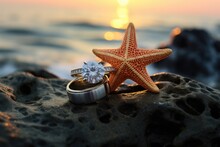 Vintage Wedding Rings Inside A Starfish Shell, Placed On A Coastal Rock At Sunset