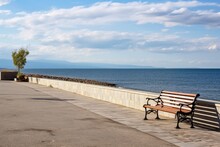 A Promenade By The Sea, With A Bench And A Bicycle