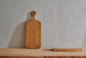 Wall Mural - Wooden cutting board on the table, kitchenware, vase of plant grey decorative wall background.